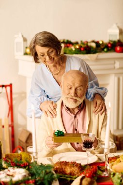 A senior couple enjoys Christmas together at home, exchanging gifts and sharing love. clipart