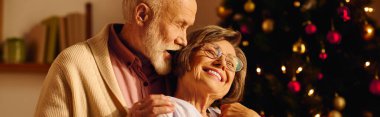 A loving senior couple celebrates Christmas together at home, surrounded by festive cheer. clipart