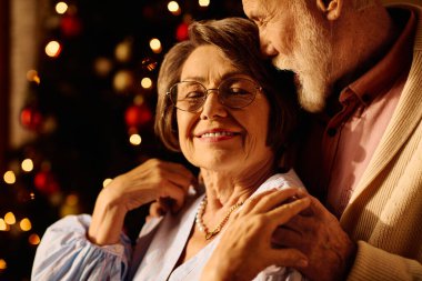 A loving senior couple enjoys a warm moment at home, embracing the spirit of Christmas. clipart