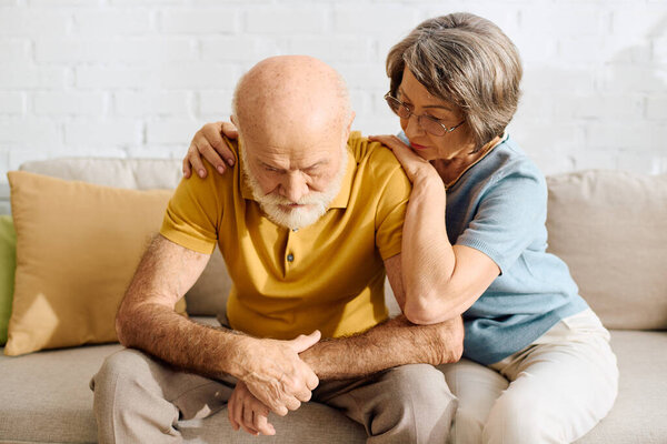A caring wife gently comforts her husband as they share a heartfelt moment at home.