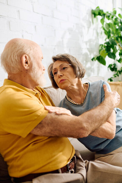 A caring wife gently comforts her husband with diabetes in their warm living room.