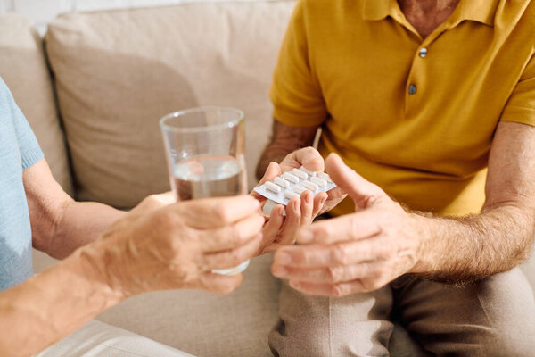 A loving wife provides her husband with medication and water in their comfortable living space.