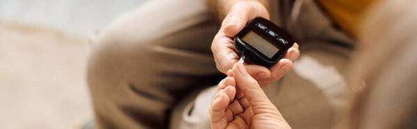 Любящая жена помогает мужу проверить сахар в крови дома, проявляя заботу..