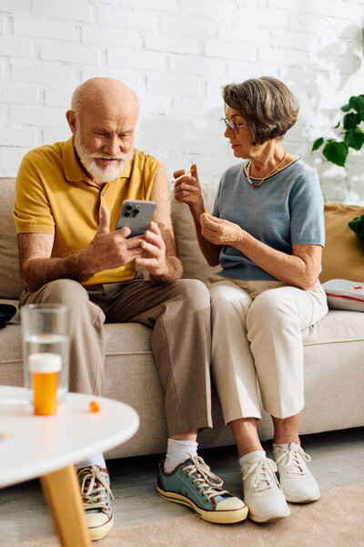 A devoted wife assists her husband with diabetes while they relax on a cozy couch together.