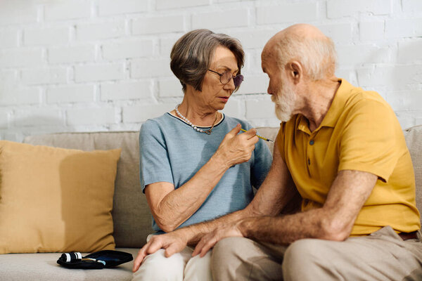 A devoted wife lovingly helps her husband manage diabetes while sitting together at home.