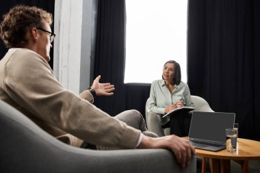 A journalist engages in a thoughtful interview with a specialist, taking notes and sipping water. clipart