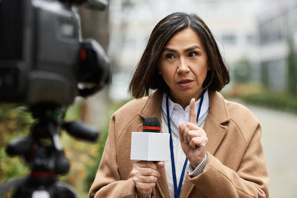A talented journalist holds a microphone and engages audiences while reporting news outdoors.