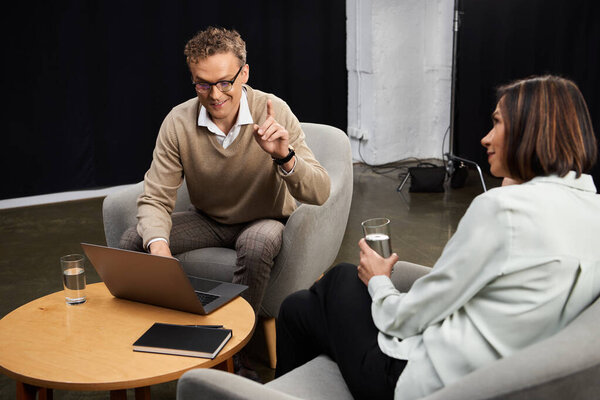 A middle-aged female journalist conducts an engaging interview with a knowledgeable specialist seated across from her.