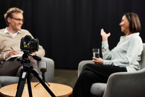 A journalist and a specialist engage in a thoughtful conversation, sharing expert insights in a cozy studio.