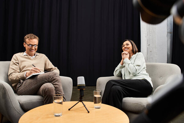 A journalist engages warmly with a specialist, sharing insights in a contemporary interview space.