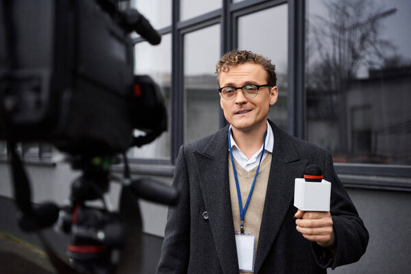Специальный журналист в очках сообщает важные новости, стоя снаружи.