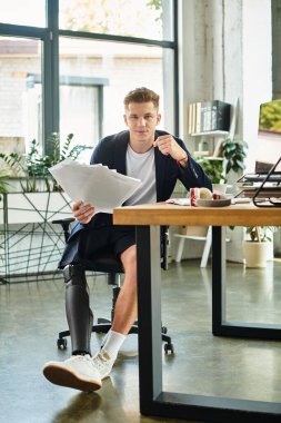 A young, professional man with a prosthetic leg is focused on his work in a contemporary office environment. clipart