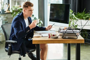 Protez bacaklı genç bir profesyonel iş dolu çağdaş bir ofis masasındaki görevlere odaklanıyor..