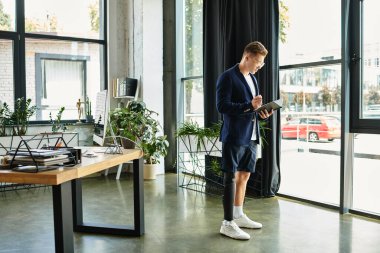 Yapay bacaklı genç ve stil sahibi bir işadamı modern bir ofiste çalışıyor..