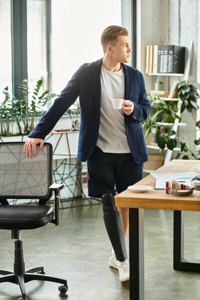 Молодой профессионал с протезной конечностью стоит в стильном офисе, держа чашку во время работы.