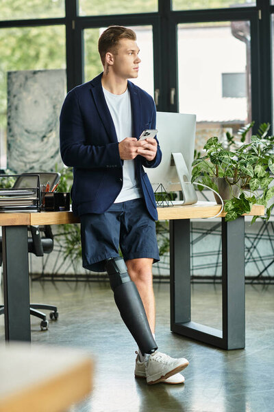 Молодой профессионал с искусственной конечностью вдумчиво взаимодействует со своим смартфоном в современном рабочем пространстве.