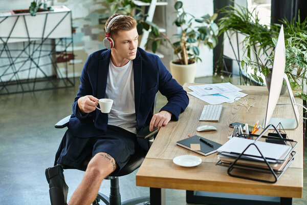 Молодой предприниматель с протезной конечностью пьет кофе, работая на рабочем месте, способствуя инклюзивности..