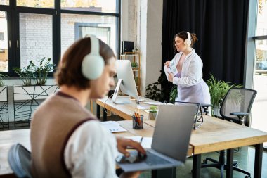 Modern ofis ortamında, genç ve iri yarı bir kadın, erkek arkadaşıyla çalışırken etkileşim halindedir..