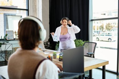 Büyük beden bir kadın, canlı bir ofis ortamındaki arkadaşıyla fikirlerini paylaşır..