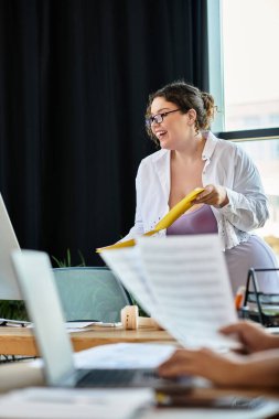 A young plus size woman animatedly shares ideas with her male friend in a stylish office. clipart