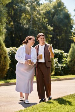 A young plus size woman and her male friend share laughter while strolling in the park. clipart