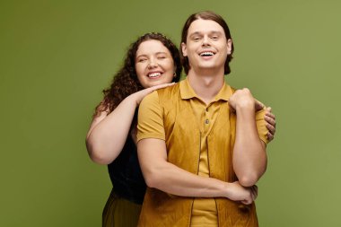 Two friends happily pose together in a studio with a bright green backdrop. clipart