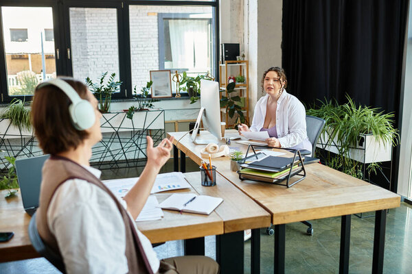 Молодая женщина плюс размер беседует со своей подругой в современном рабочем пространстве, заполненном зеленью.