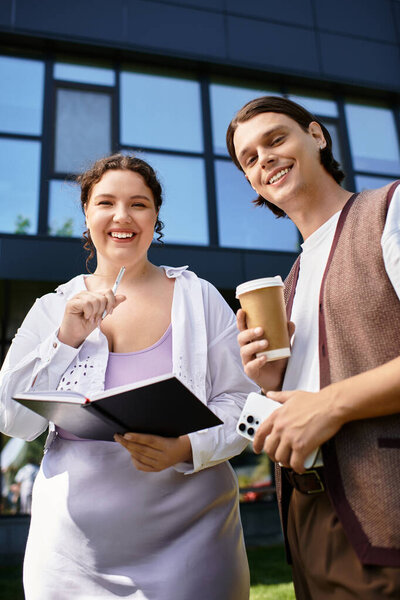A cheerful young woman and her friend enjoy a joyful moment with coffee and a notebook.