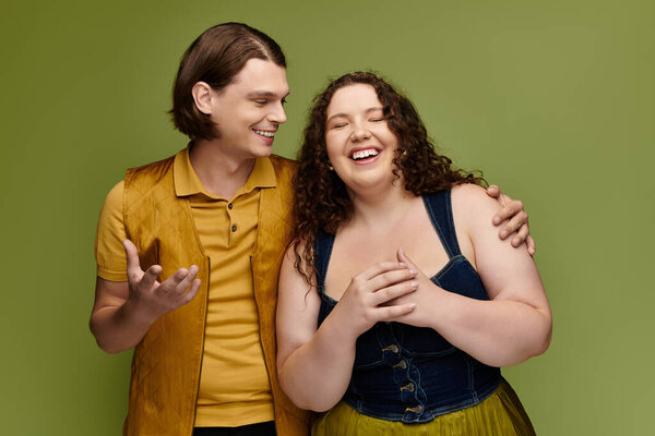 A young plus size woman laughs with her male friend in a lively and colorful atmosphere.