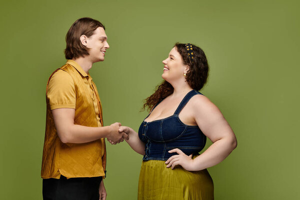 A young plus size woman and her male friend share a friendly handshake in a lively atmosphere.