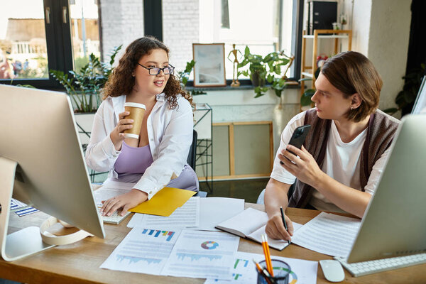 Молодая женщина счастливо болтает со своим другом за чашечкой кофе на рабочем месте.