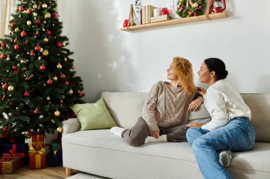 Neşeli bir çift, tatil neşesi ve süslemelerle çevrili kanepede birlikte dinlenir..