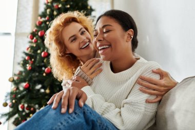 İki sevecen eş, evlerindeki Noel ağacının yanında gülüşlerini ve sıcaklığını paylaşıyor..