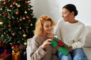 Two women enjoy a heartfelt moment together while exchanging a beautifully wrapped gift. clipart