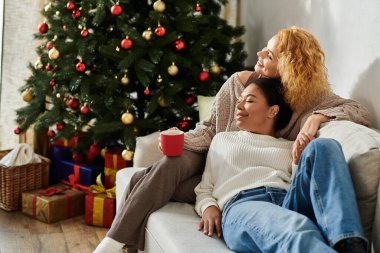 Sevgi dolu bir çift, Noel ağacının yanında sıcak bir içkinin tadını çıkarır..