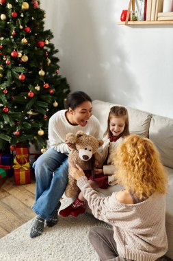 A joyous lesbian couple shares special Christmas moments with their young daughter at home. clipart