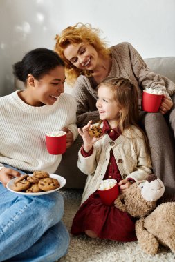Mutlu bir aile evde birlikte dinlenirken kurabiye ve sıcak içeceklerden hoşlanır..