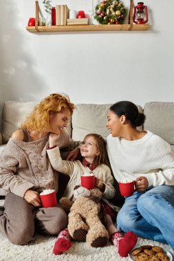 Neşeli bir aile sıcak bir anın tadını çıkarır, gülümsemelerini ve sıcak içkilerini evde paylaşırlar..