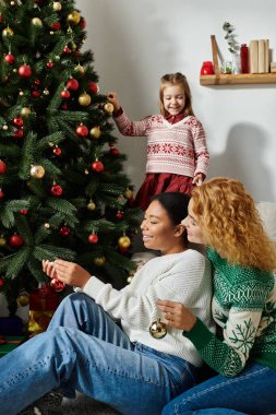 Sevgi dolu bir çift Noel ağacını neşeli kızlarıyla süslemekten zevk alır..