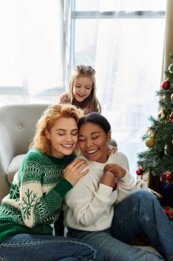 Sevgi dolu bir çift, kızlarıyla birlikte evdeki süslü Noel ağacının yanında gülümsüyor..
