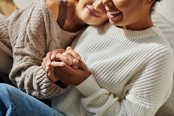 Two women smile gently while holding hands, enjoying each others warmth and connection.