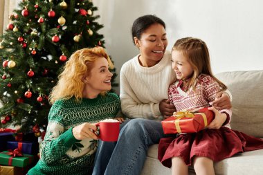 Neşeli bir lezbiyen çift Noel 'i kızlarıyla geçirir, birbirlerine gülümseyerek ve hediyeler vererek..