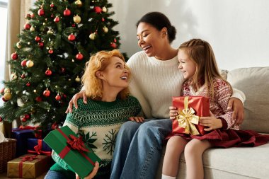 Güzel bir çift, kızlarına Noel hediyesi verirken gülüşlerini paylaşır..