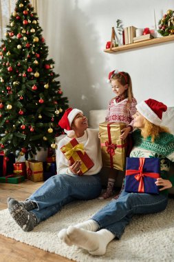 Neşeli bir aile Noel 'i birlikte kutlar, hediyelerini paylaşır ve rahat evlerinde gülümserler..