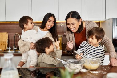 Asyalı bir aile, modern bir mutfakta yetişkinlere yardım eden çocuklarla birlikte bayram ziyafeti hazırlıyor..