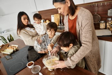 Neşeli bir aile malzemeleri harmanlarken, çocuklar da hevesle mutfaklarında yemek pişirmeye katılıyorlar..