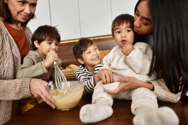 Neşeli bir aile, modern mutfaklarında Noel için hazırlanan sevimli çocuklarla tatil pişirme seansının keyfini çıkarıyor..