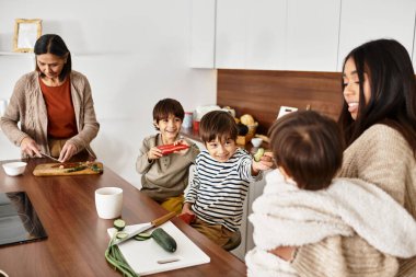 Çocuklar yetişkinlerin Noel şenliklerine hazırlanmasına yardım ederken bir aile yemek pişirmenin keyfini çıkarır..