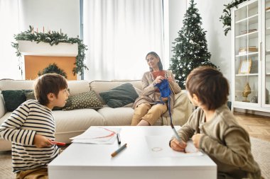 Neşeli bir Asyalı aile Noel ağacının yanında toplanıyor, kahkahaları, sevgiyi ve tatil ruhunu paylaşıyorlar..