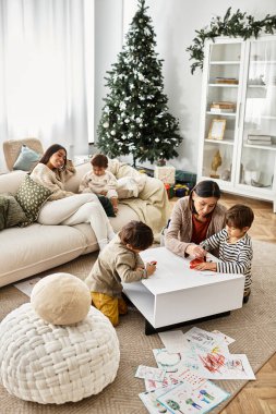 Mutlu bir aile, modern bir mekanda Noel ağacının etrafında el sanatları yaparak, birlikte kaliteli vakit geçirmekten zevk alır..